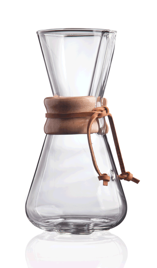 Et klart glas Chemex, Classic Kaffebrygger 3-kopper (CM-1C) med en trækrave og læderslips er vist mod en hvid baggrund. Kaffemaskinen har timeglasform og en bred åbning i toppen, perfekt til at mestre pour-over teknik.