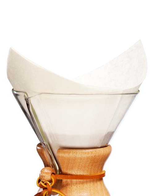 En Chemex Barista Pakke (6 pax) fra Chemex & EverBean, med en trækrave og et læderslips, er fremvist. Et papirfilter (filtre til Chemex) er pænt placeret inde i glaskaraflen, klar til brygning af kaffe. Den almindelige hvide baggrund fremhæver elegancen af denne brygger, der er ekspertdesignet til at lave udsøgt Kenya-kaffe.