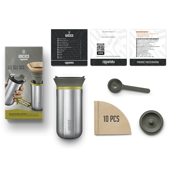 Et billede af Wacaco Cuppamoka pour-over kaffebryggesæt. Sættet inkluderer et spildsikkert rejsekrus, kaffefilterholder, scoop, pakke med 10 papirfiltre og en instruktionsbog. Emballagen og alle varer vises i et fladt liggende arrangement.