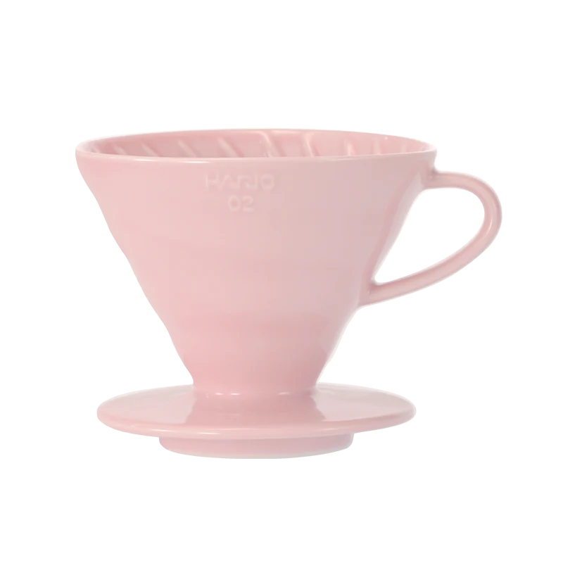 En pink Hario, Keramisk Drip Tragt med et håndtag, perfekt til kaffeeksperter. Den er lavet til pour-over-brygning, og den har en konisk form med indvendige kanter og markeret som "Hario 02" på siden.