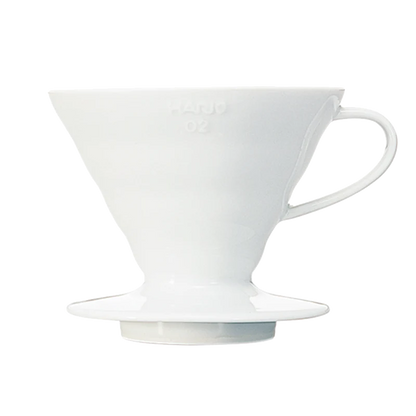 Hario Keramisk Drip Tragt er en hvid keramisk kaffedrypper med et håndtag, designet til pour-over brygning. Den viser den ikoniske HARIO V60-kegleform og delikate spiralriller mod en almindelig baggrund.