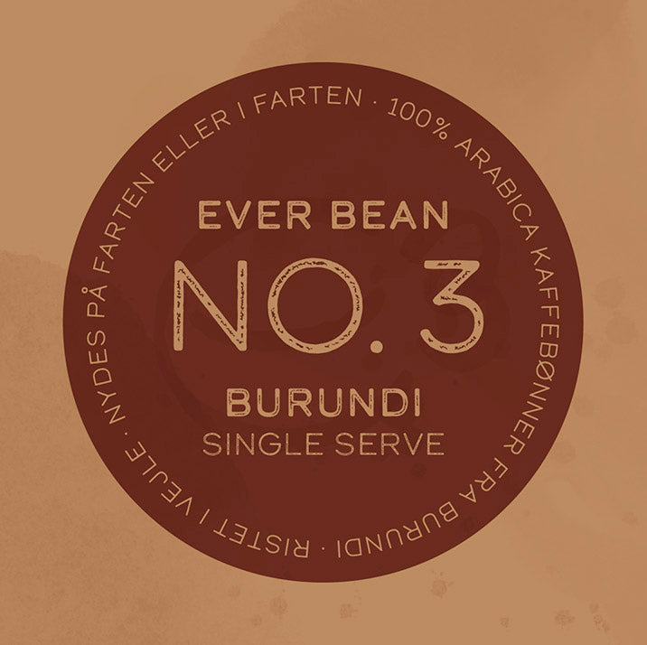 Brun cirkulær etiket læser: "Enkeltservering (w) EverBean Burundi." Yderligere cirkulær tekst siger: "100% Arabica Kaffebønner fra Burundi. Specialkaffe - Ristet, nydes på farten eller i farten.".